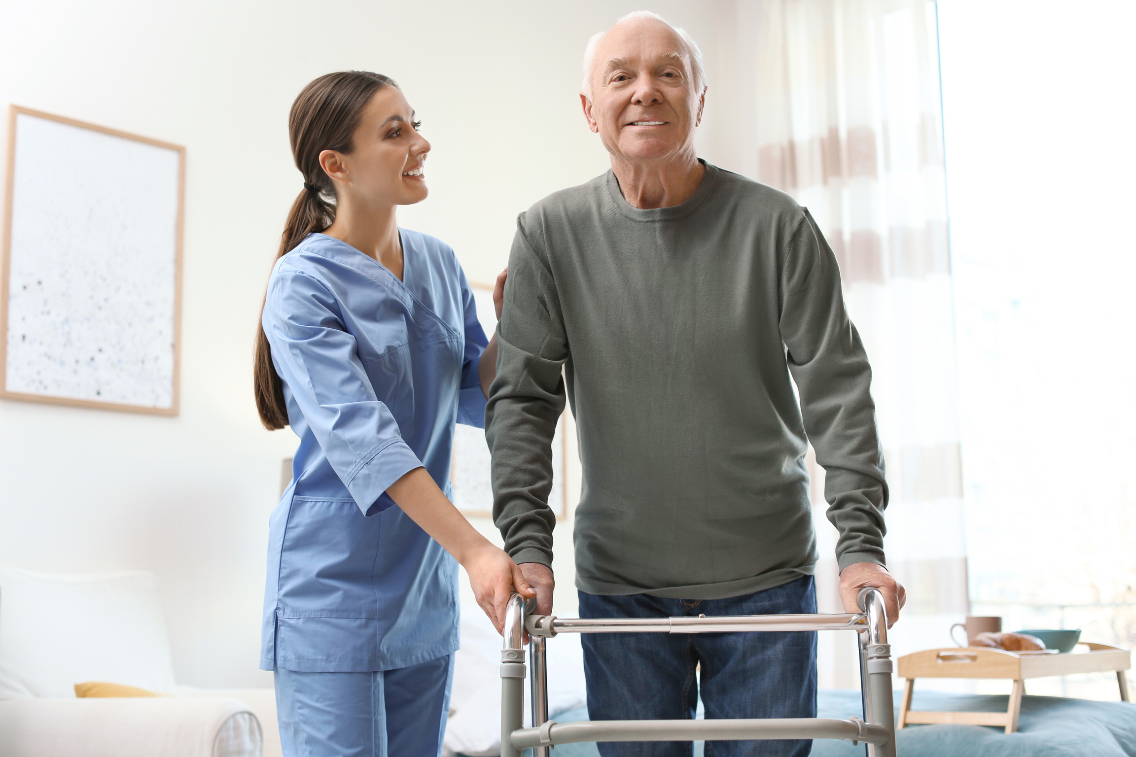 Care Worker Helping Elderly Man with Walker in Geriatric Hospice